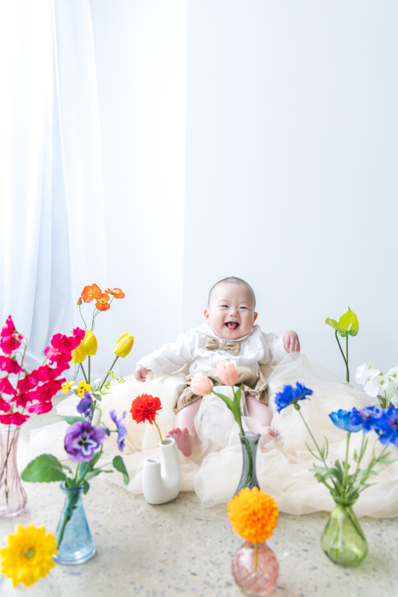 赤ちゃんも笑顔になるカラフルな花の装飾で撮影。墨田区の子供写真館・花と星フォトスタジオ。