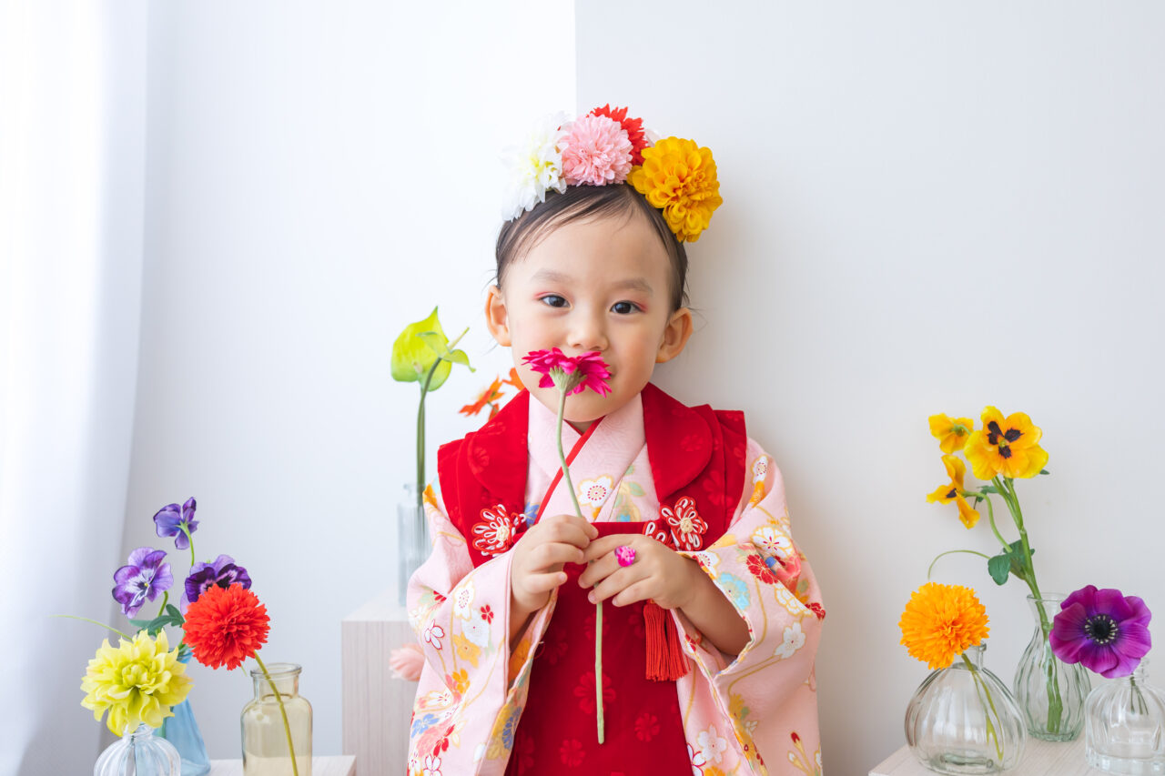 白い壁とカラフルなお花と着物の女の子3歳七五三